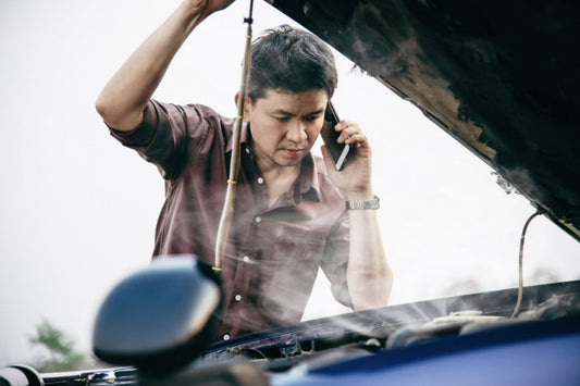 A man calling for roadside assistance because of overheating engine